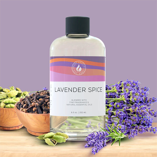 Lavender Spice diffuser oil in an 8.5 oz bottle, displayed with fresh lavender, clove, and cardamom to reflect its warm botanical blend.