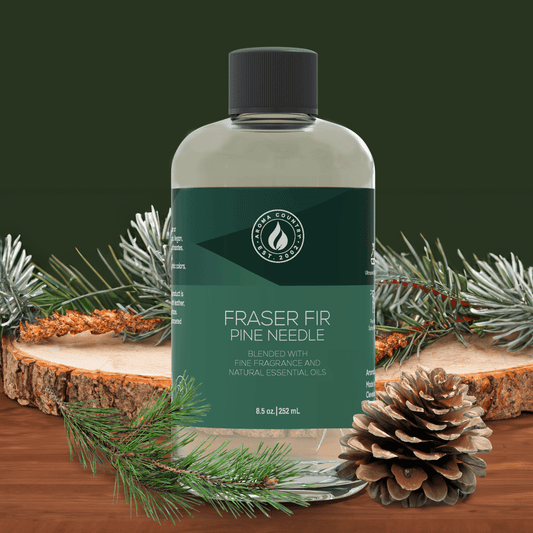 Fraser Fir Pine Needle diffuser oil from Aroma Country in an 8.5 oz bottle, surrounded by pinecones, fir branches, and wood slices for a fresh, forest-inspired holiday scent.